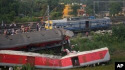 Onlookers are seen gathered as crews work at the site of a deadly train derailment in Balasore district, in the eastern Indian state of Odisha, June 4, 2023.