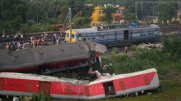 Onlookers are seen gathered as crews work at the site of a deadly train derailment in Balasore district, in the eastern Indian state of Odisha, June 4, 2023.