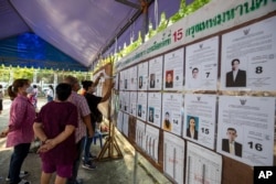 Pemilih memeriksa informasi kandidat di TPS di Bangkok, Thailand, 14 Mei 2023. (Foto: AP)