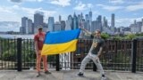 Батько Геник із сином Фредом вітають українців зі святом. Вони розгорнули прапор України на тлі острова Мангеттен, штат Нью-Йорк.