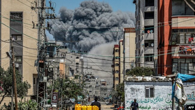 FILE - A cloud of smoke billows down the road from an Israeli airstrike in the central Gaza Strip on April 17, 2024.