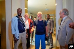 Released hostages French journalist Olivier Dubois, left, and American aid worker Jeffery Woodke, center, arrive at the VIP lounge at the airport in Niamey, Niger, March 20, 2023.