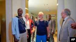FILE- Released hostages French journalist Olivier Dubois, left, and American aid worker Jeffery Woodke, center, arrive at the airport in Niamey, Niger, March 20, 2023.