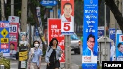 Orang-orang berjalan melewati poster kampanye pemilu di Bangkok, sementara Thailand akan mengadakan pemilihan umum pada 14 Mei mendatang. 