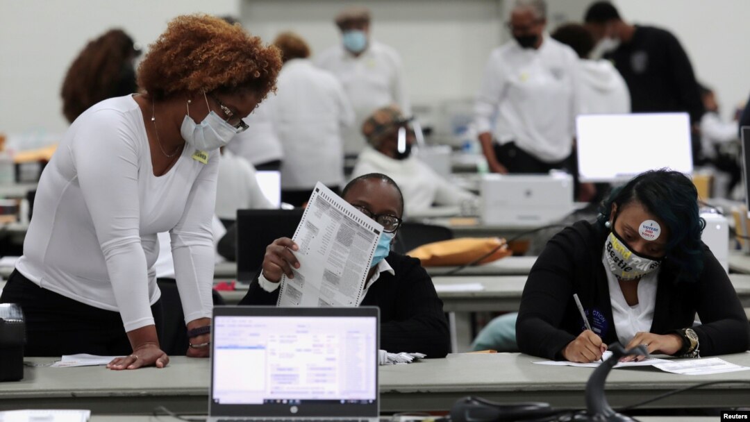 FILE - Poll workers tabulate absentee ballots at the TCF Center during Election Day in Detroit, Nov. 3, 2020.