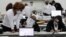 FILE - Poll workers tabulate absentee ballots at the TCF Center during Election Day in Detroit, Nov. 3, 2020.