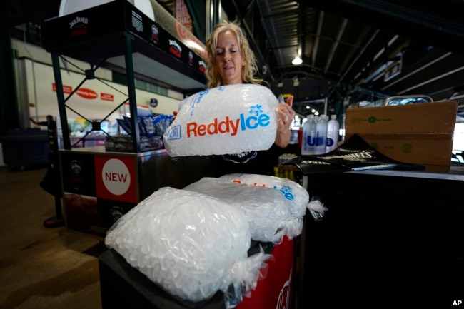 Cheryl Batch picks up a bag of ice to use to cool beverages at a stand on the main concourse of Coors Field before the Colorado Rockies host the Pittsburgh Pirates in a baseball game Sunday, June 16, 2024, in Denver. (AP Photo/David Zalubowski)