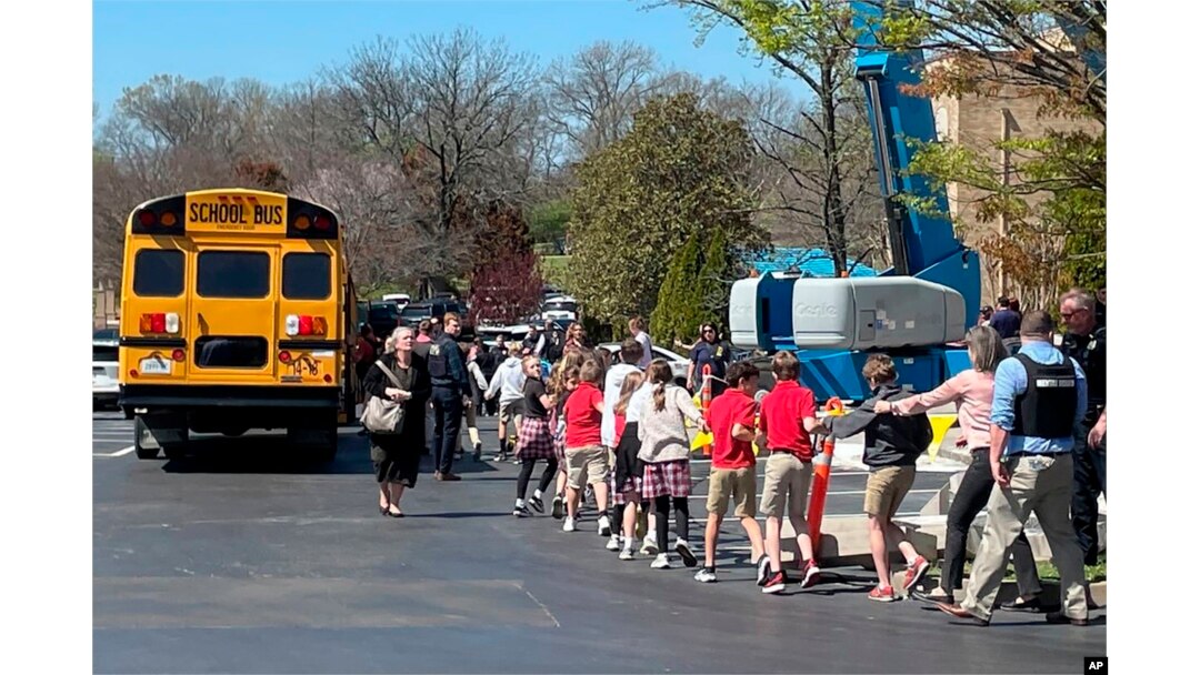 Children from The Covenant School hold hands as they are taken to a reunification site at the Woodmont Baptist Church after a deadly shooting at their school, in Nashville, Tennessee, March 27, 2023.