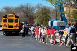 Children from The Covenant School hold hands as they are taken to a reunification site at the Woodmont Baptist Church after a deadly shooting at their school, in Nashville, Tennessee, March 27, 2023.