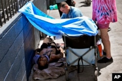 Dr. Matt Essary checks on a homeless man who fell ill on the sidewalk outside one of five Circle The City mobile clinics stationed outside soup kitchens and other services for homeless people, May 30, 2024 in Phoenix, Arizona.