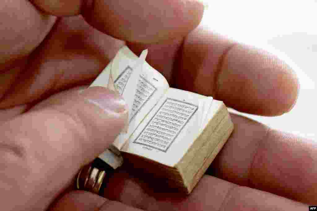 Mario Prushi holds one of the smallest versions of the Quran - the size of a postage-stamp size - with a cover crafted from gold embroidered velvet, in Tirana, Albania.