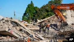 FILE - Rescue personnel search the site of a building collapse in George, South Africa, May 9, 2024.