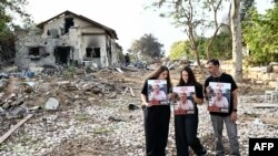 FILE - Relatives of Ohad ben Ami, 65, an Israeli hostage held in the Gaza Strip since the October 7 attack by Hamas, pose for a picture with his portrait during a visit to Kibbutz Beeri in southern Israel near the border with Gaza on on December 20, 2023. 