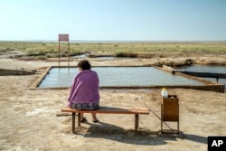 A woman relaxes next to a hot spring, in an area that used to be part of the Aral Sea, near Aralsk, Kazakhstan, July 3, 2023.