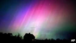 The northern lights flare in the sky over a farmhouse, late Friday, May 10, 2024, in Brunswick, Maine. (AP Photo/Robert F. Bukaty)