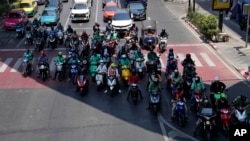 FILE - Motorcyclists stop in the shade of a skytrain line on a hot day in Bangkok, Thailand, May 3, 2024.