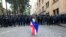 A demonstrator with draped Georgian national and EU flags stands in front of police blocking the way to the Parliament building, during an opposition protest against what has been dubbed "the Russian law," in the center of Tbilisi, Georgia, May 14, 2024.