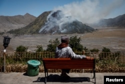 Seorang pria menyaksikan asap membubung dari Gunung Batok, di Taman Nasional Bromo Tengger Semeru, Probolinggo, Jawa Timur, 22 Juni 2024. (REUTERS/Willy Kurniawan)