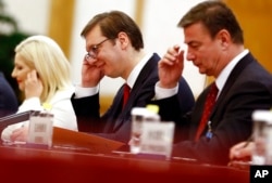 FILE - Serbian Prime Minister Aleksandar Vucic, center, adjusts an earphone as he attends a meeting with Chinese President Xi Jinping at the Great Hall of the People in Beijing, May 16, 2017. Xi will visit Serbia this week on his European tour.