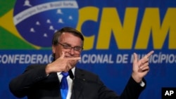FILE - Brazil's President Jair Bolsonaro points his fingers as if they were guns as he addresses the National Mayor's Meeting in Brasilia, Brazil, April 26, 2022. He repeatedly claimed that "an armed populace will never be enslaved."