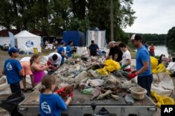 Para relawan secara selektif memilah sampah yang dikumpulkan setibanya di lokasi perkemahan, Selasa, 1 Agustus 2023. Kompetisi Piala Plastik tahunan ini telah mengumpulkan sekitar 330 ton sampah dari Tisza sejak tahun 2013. (AP/Denes Erdos)