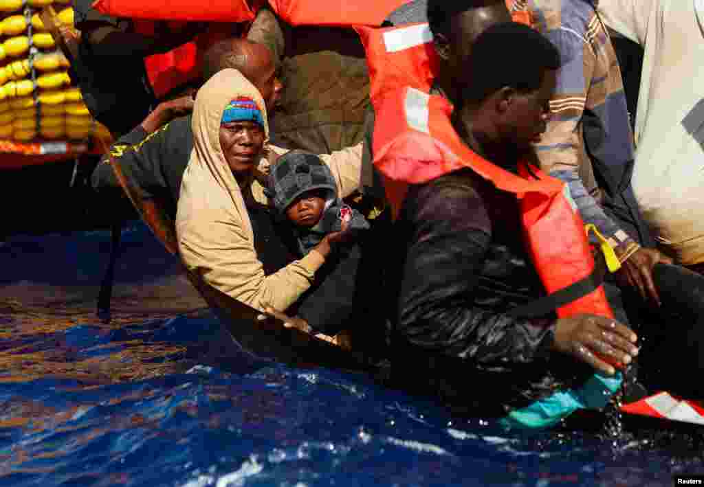 A migrant holds her baby on a small iron boat during a rescue by the Geo Barents migrant rescue ship, operated by Medecins Sans Frontieres (Doctors Without Borders), in international waters between Tunisia and Lampedusa, in the central Mediterranean Sea, July 20, 2024.&nbsp;