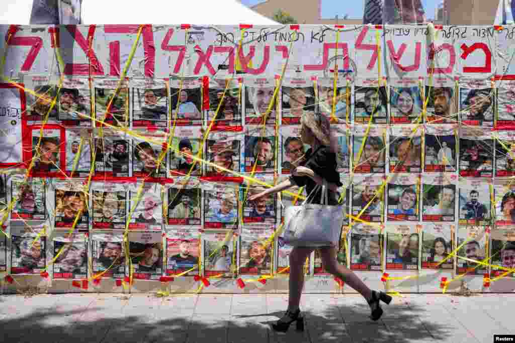 A person walks past pictures of hostages kidnapped during the deadly October 7 attack on Israel by Hamas, amid the ongoing Israel-Hamas conflict, in Tel Aviv, Israel.