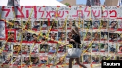 Seorang pejalan kaki melintas di depan foto-foto orang Israel yang disandera oleh kelompok Hamas Palestina saat serangan 7 Oktober, di tengah konflik Israel-Hamas, di Tel Aviv, Israel, 10 Juni 2024. (Foto: Marko Djurica/Reuters)