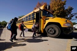 Siswa SD Highland di Columbus, Kansas, naik bus sekolah yang akan mengantar mereka pulang usai sekolah, Senin, 17 Oktober 2022. (AP/Charlie Riedel)