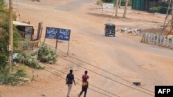 People walk on a deserted street in Khartoum, Apr. 30, 2023, as clashes continue in war-torn Sudan. 