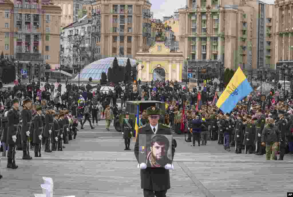 A serviceman carries a photo of Ukrainian officer Dmytro Kotsiubaylo, code-named "Da Vinci," during a commemoration ceremony in Independence Square in Kyiv, Ukraine. Kotsiubaylo was killed three days ago in a battle near Bakhmut in the Donetsk region.