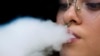 FILE - A woman blows smoke from an electronic cigarette in San Jose, Costa Rica, on May 14, 2024. 