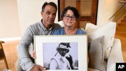 FILE - Derek and Suzi Alkonis pose with a photo of their son, Lt. Ridge Alkonis, in Dana Point, California, June 1, 2022.