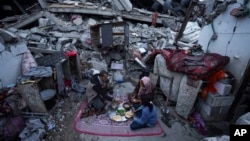 Members of the Al-Rabaya family break their fast during the Muslim holy month of Ramadan outside their home, destroyed by Israeli airstrikes, in Rafah, Gaza Strip, March 18, 2024.