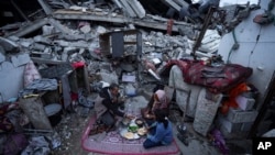 2024年3月18日，加沙地带拉法的一户人家于穆斯林斋月期间在被以色列空袭摧毁的家外用餐。（美联社照片）