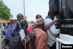Nigerien nationals board a bus to travel to neighboring countries as thousands of trucks carrying aid wait, due to sanctions imposed by Niger's regional and international allies, in the border town of Malanville, Benin, Aug. 17, 2023.