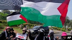 Indonesian Muslim women wave Palestinian flags during a rally in support of Palestinians, in Jakarta, Indonesia, Oct. 13, 2023. 