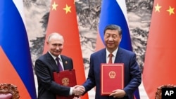 In this photo released by Xinhua News Agency, Chinese President Xi Jinping, right, and Russian President Vladimir Putin attend a signing ceremony at the Great Hall of the People in Beijing, May 16, 2024.