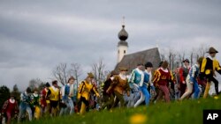 Local residents of the region wearing traditional costumes make their way to get blessings for men and animals, at the St. George church in Traunstein, Germany. (AP Photo/Matthias Schrader)