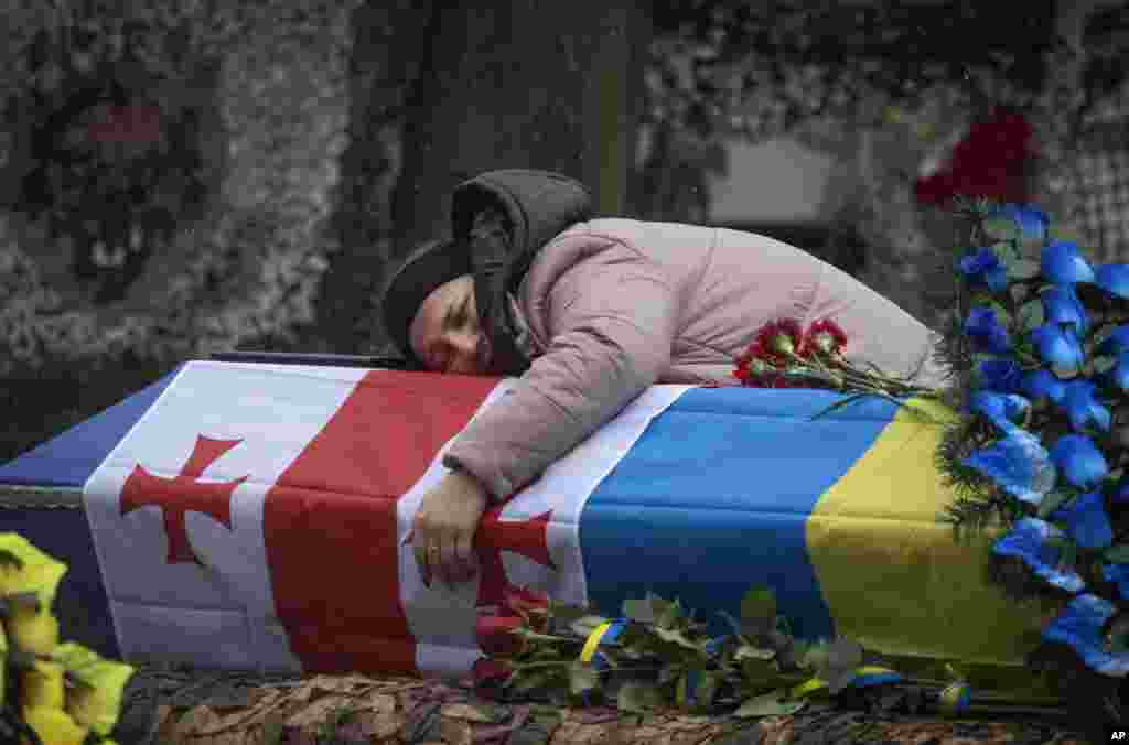 A relative mourns over a coffin of Nodar Nasirov, 28, a volunteer of the Georgian legion who was killed in a battle against Russian troops, during a funeral ceremony in Kyiv, Ukraine. (AP Photo/Efrem Lukatsky)