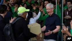 Apple CEO Tim Cook, right, reacts after seeing an old old Macintosh Classic machine brought by a visitor during the opening of the first Apple Inc. flagship store in Mumbai, India, April 18, 2023.