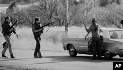 FILE - FBI agents stop a man at a roadblock near Wounded Knee, South Dakota, in 1973.