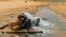 Un migrant d'origine africaine boit de l'eau à son arrivée dans une zone inhabitée près d'al-Assah à la frontière libyo-tunisienne le 30 juillet 2023.