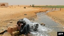Un migrant d'origine africaine boit de l'eau à son arrivée dans une zone inhabitée près d'al-Assah à la frontière libyo-tunisienne le 30 juillet 2023.