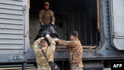 Members of a Ukrainian Civil-Military Cooperation team load the remains of a Russian soldier into a railroad car in the village of Synykha, in Ukraine's Kharkiv region, April 8, 2023, amid Russia's invasion of its neighbor.