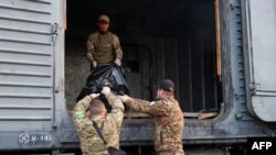 Members of a Ukrainian Civil-Military Cooperation team load the remains of a Russian soldier into a railroad car in the village of Synykha, in Ukraine's Kharkiv region, April 8, 2023, amid Russia's invasion of its neighbor.