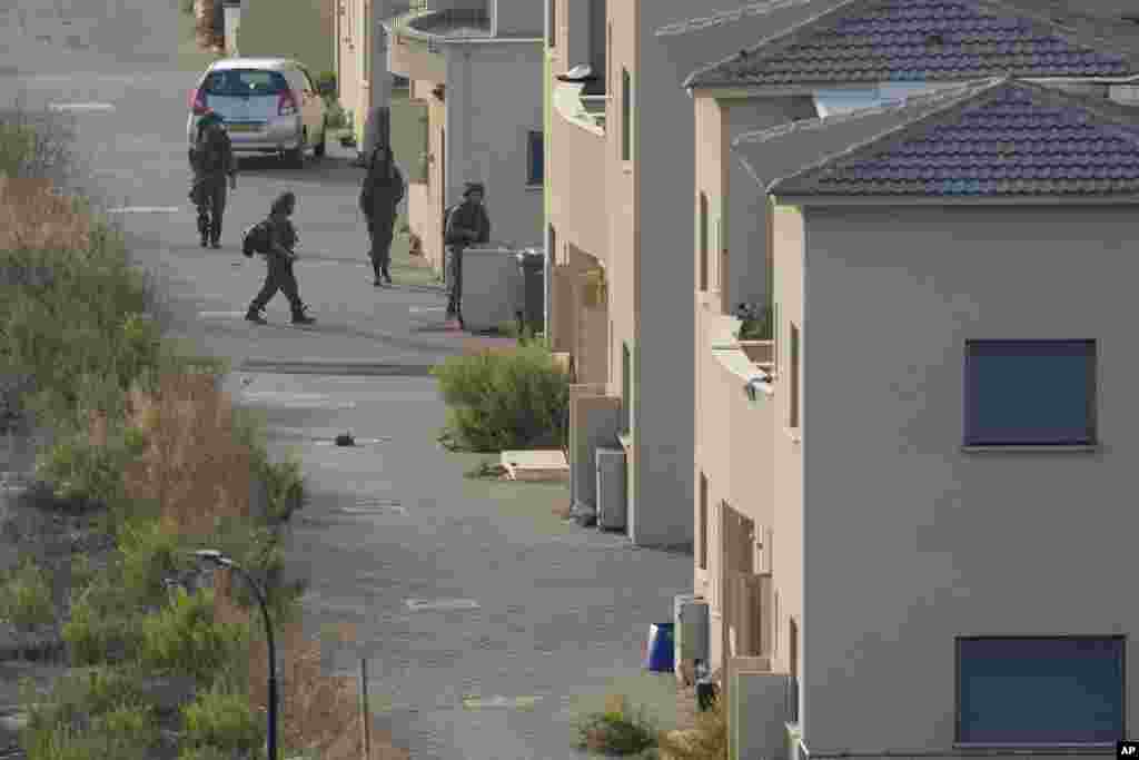 Israeli soldiers deploy between the houses in the Israeli town of Metula, as seen from the Lebanese side of the Lebanese-Israeli border in the southern village of Kfar Kila, Lebanon, Oct. 8, 2023. 