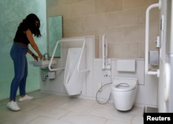 Seorang turis asing melihat-lihat toilet umum yang didesain ulang sebagai bagian dari proyek mengubah toilet umum menjadi toilet yang dapat digunakan dengan nyaman oleh semua orang, di kawasan Shibuya, di Tokyo, Jepang, 4 April 2024. (REUTERS/Kim Kyung-Hoon)