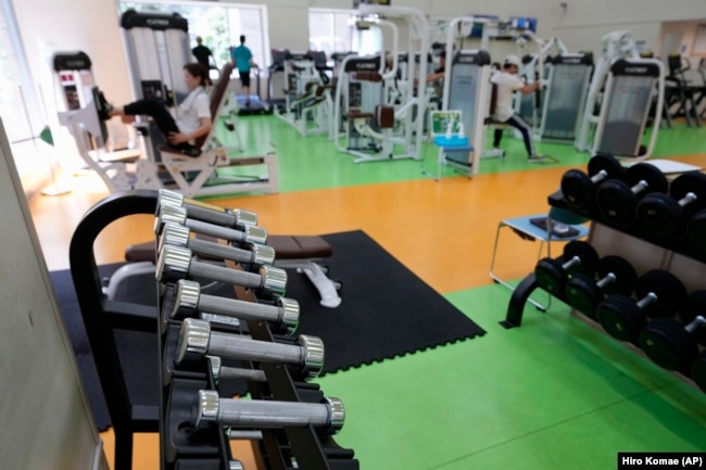 At a gym, you can use free weights (seen in the foreground) or weight machines (seen in the background.) People work out at the Fukagawa Sports Center in Tokyo, Wednesday, June 12, 2024. (AP Photo/Hiro Komae)