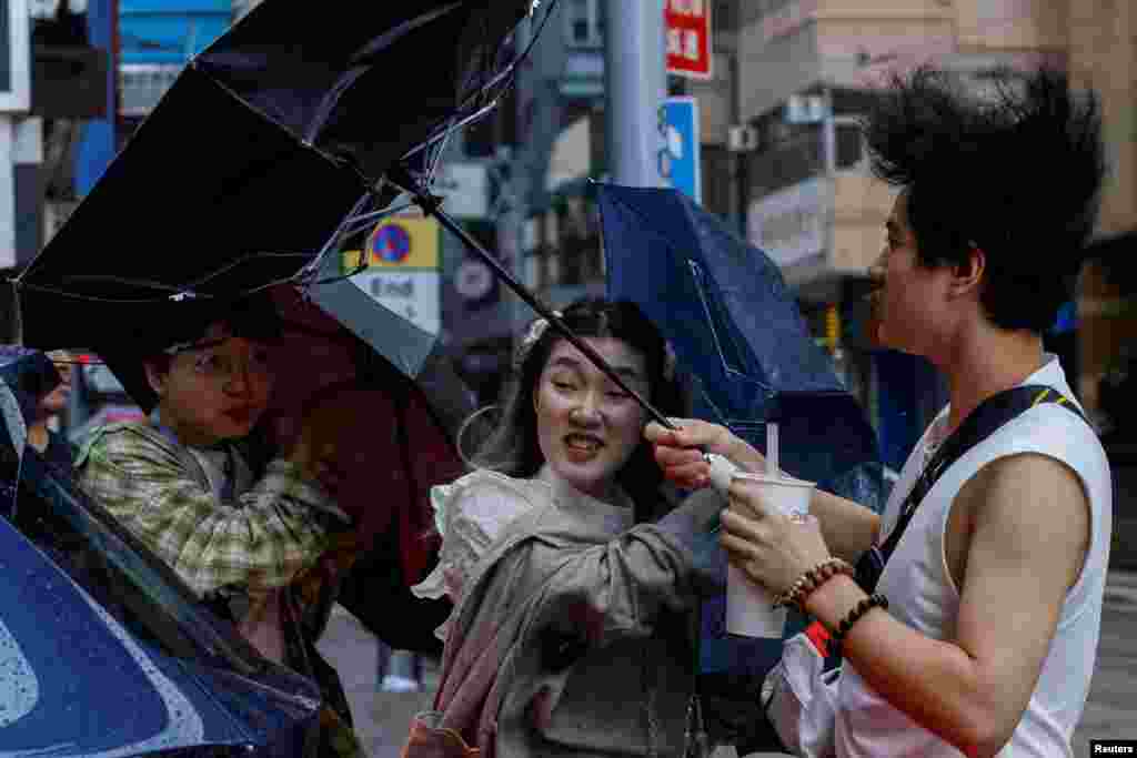 People struggle with umbrellas while walking against strong wind as Typhoon Koinu approaches, in Hong Kong, China.
